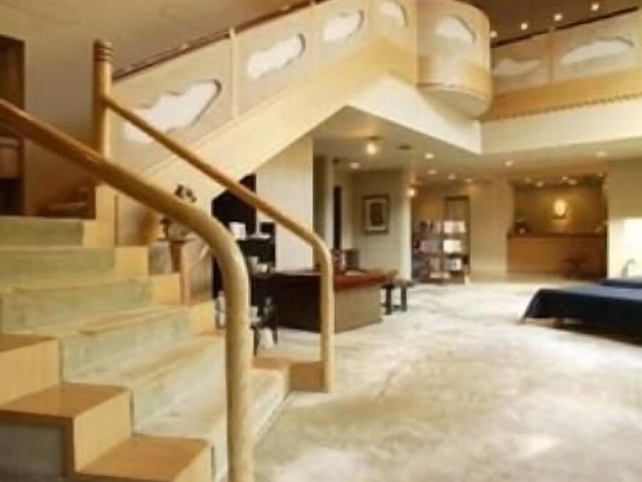 A spacious interior with a curved staircase, a large seating area, and a high ceiling.
