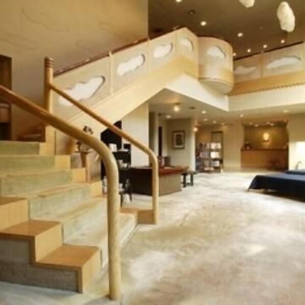 A spacious interior with a curved staircase, a large seating area, and a high ceiling. - Kounkan (Shibukawa)