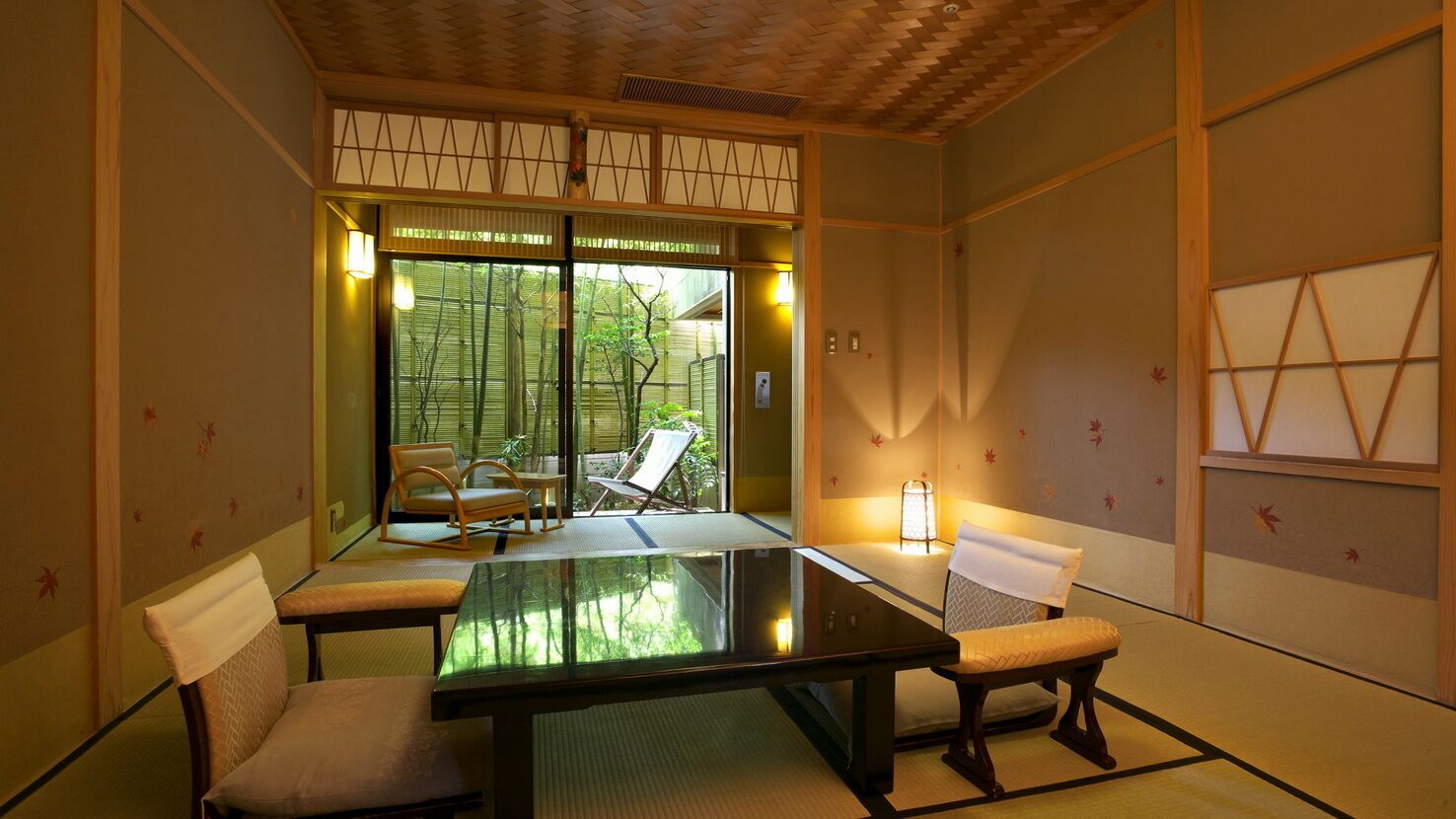 A traditional Japanese room with tatami flooring, a low table, and sliding doors leading to an outdoor area with a view of trees and a garden.