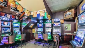 Un espace de jeux équipé de plusieurs machines à sous, de chaises et de panneaux publicitaires.