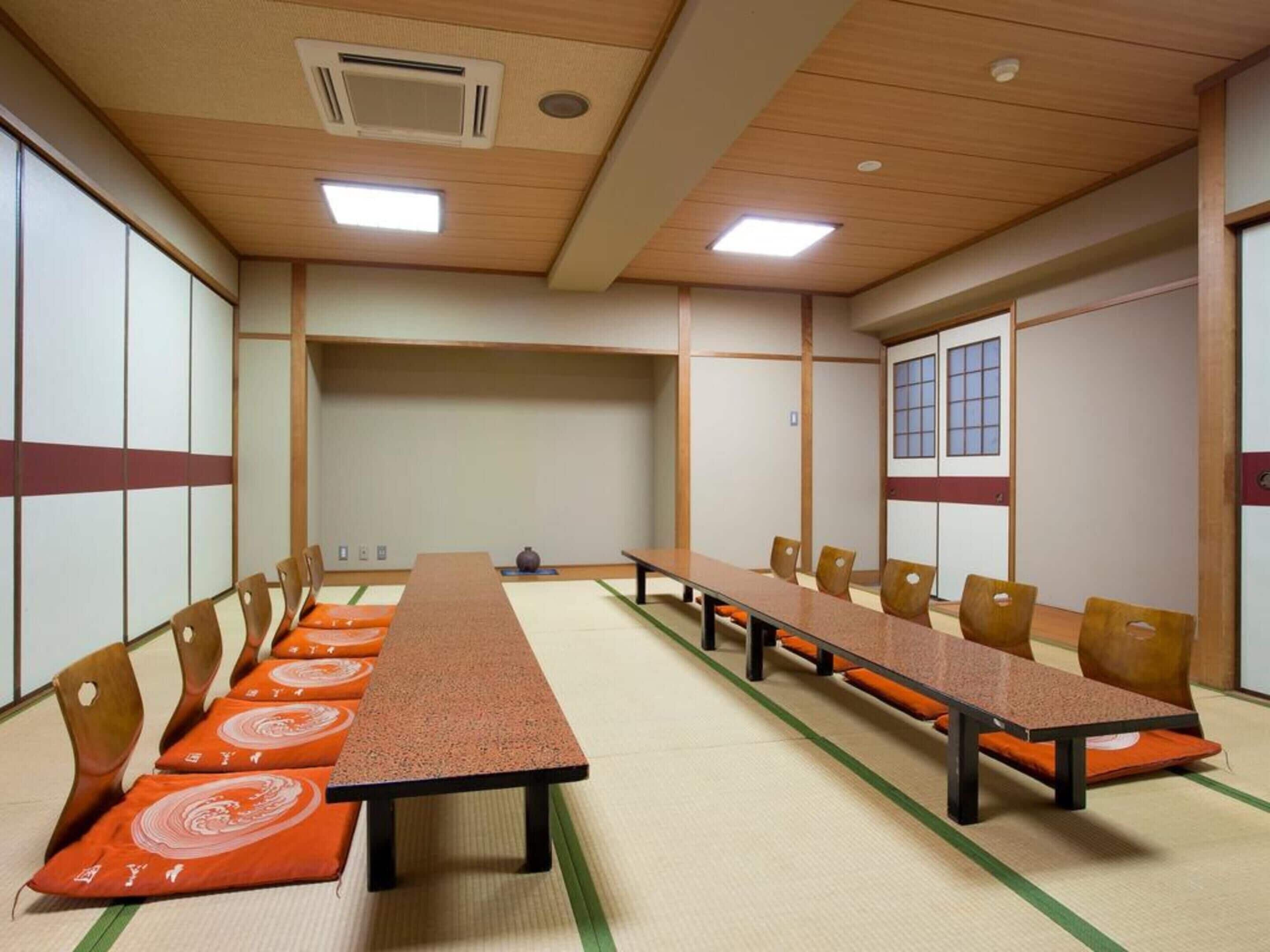 A conference room with a long table, chairs, tatami mats, and shoji screens.