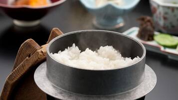 Un tazón de metal con arroz blanco cocido sobre un plato negro.