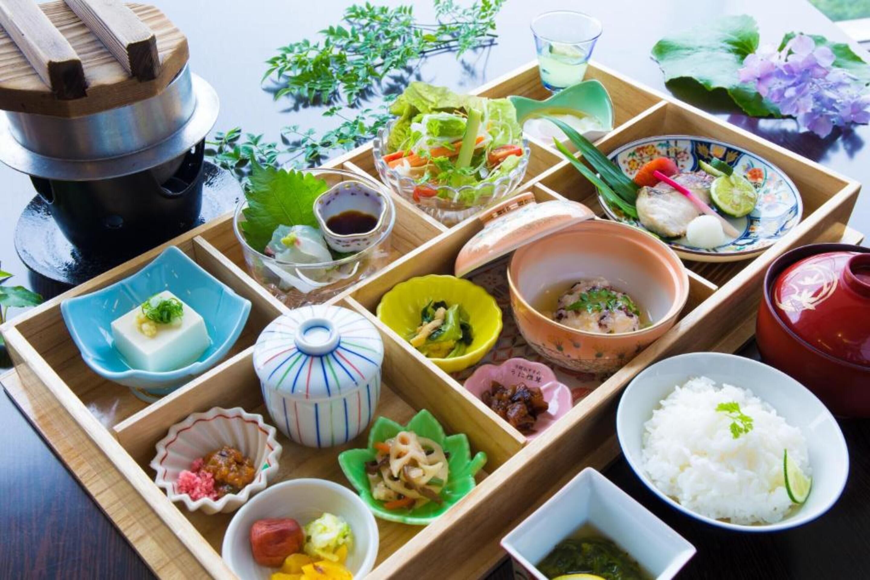 A traditional Japanese meal set with various dishes and utensils on a wooden tray.