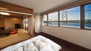 A hotel room with tatami flooring, a bed, a TV, and a large window offering a view of a bridge. - Bay Resort Hotel Naruto Kaigetsu (Naruto)