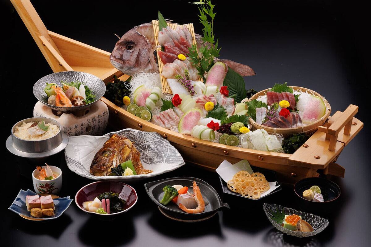 A variety of Japanese dishes, including sashimi, rice, and seafood, arranged on a table.