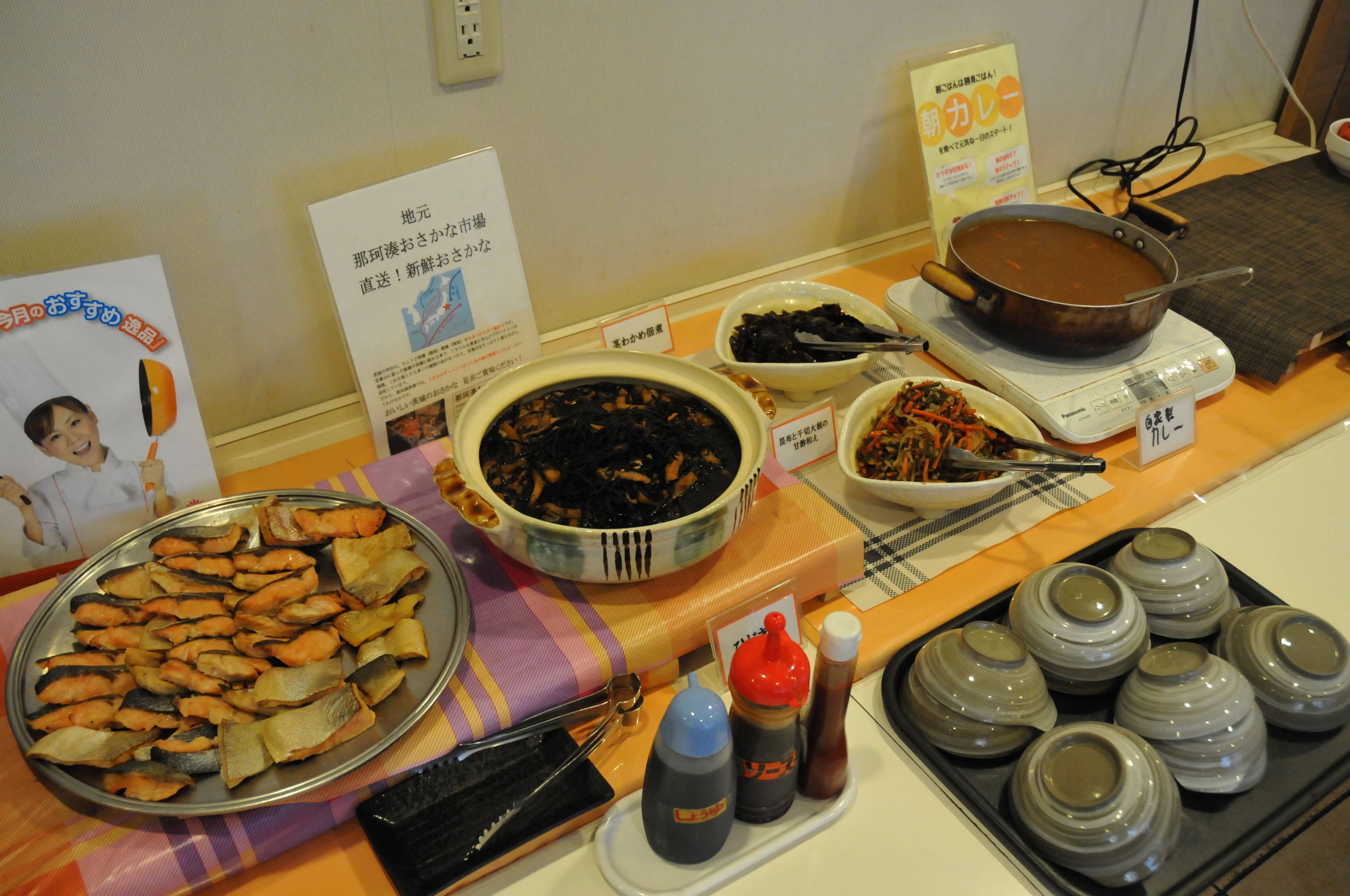 A buffet table with various dishes and condiments.