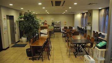 A restaurant with multiple tables and chairs, a large potted plant, and a coffee machine.