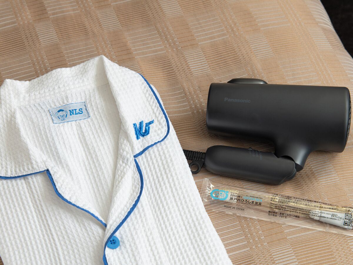 A white shirt with blue piping and a black hairdryer on a patterned surface.