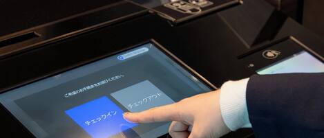 A digital interface on a kiosk, likely for hotel check-in or information, with a hand interacting with it.