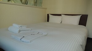 A neatly made bed with white linens and folded towels. - Hotel Green City (Sendai)