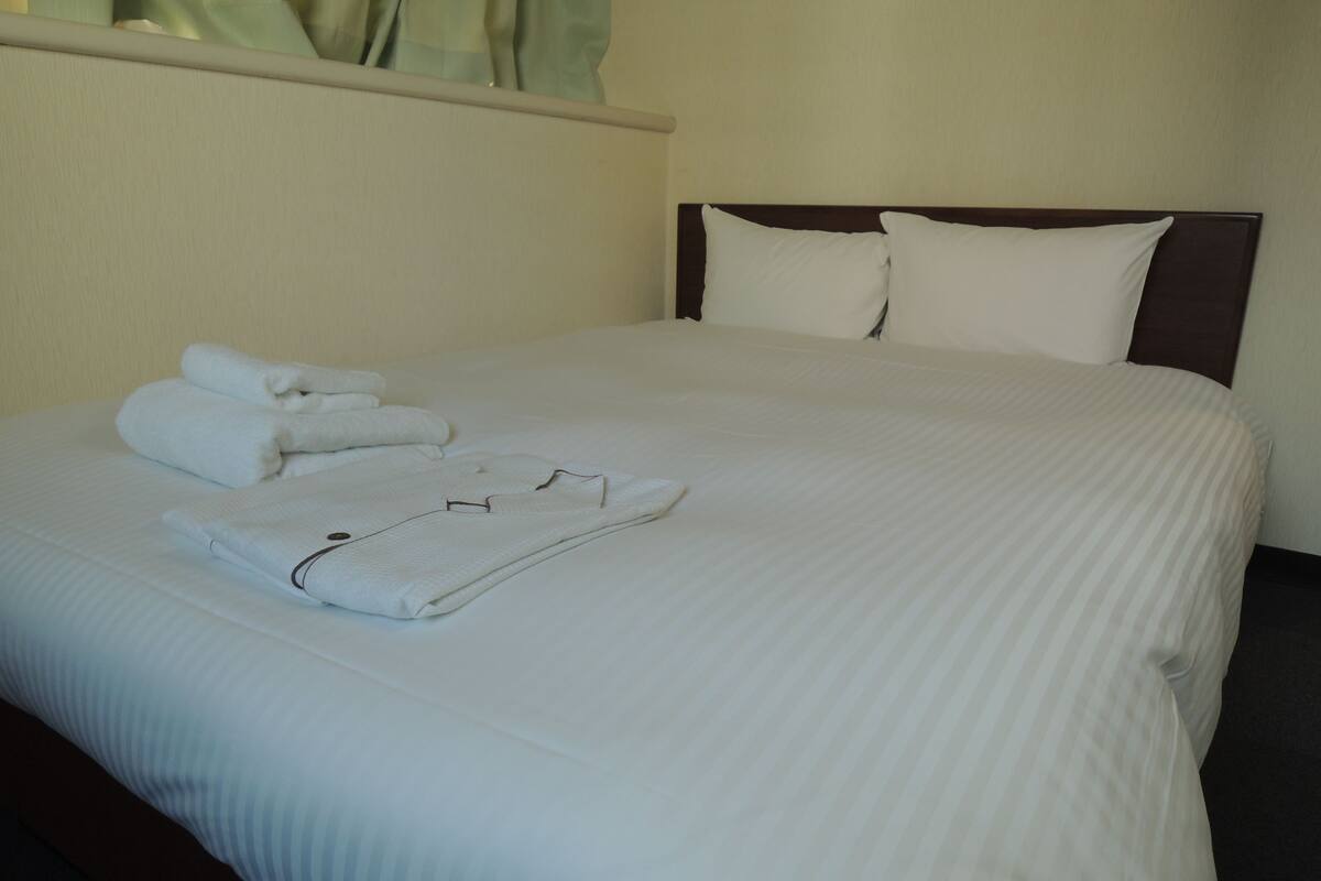 A neatly made bed with white linens and folded towels.