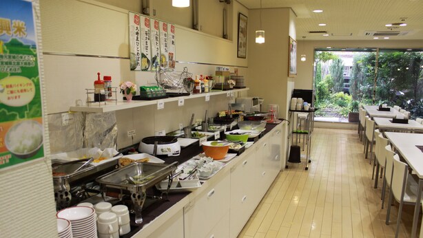 A buffet setup with various food stations and a view of the garden outside. - Hotel Green City (Sendai)