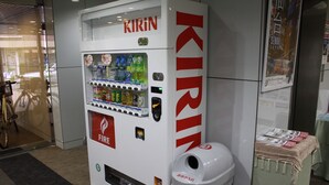 A vending machine with a Kirin logo, a fire extinguisher, and a trash bin. - Hotel Green City (Sendai)