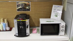 Una máquina de café y un microondas sobre una encimera con pared de paneles de madera, un cartel y un letrero.