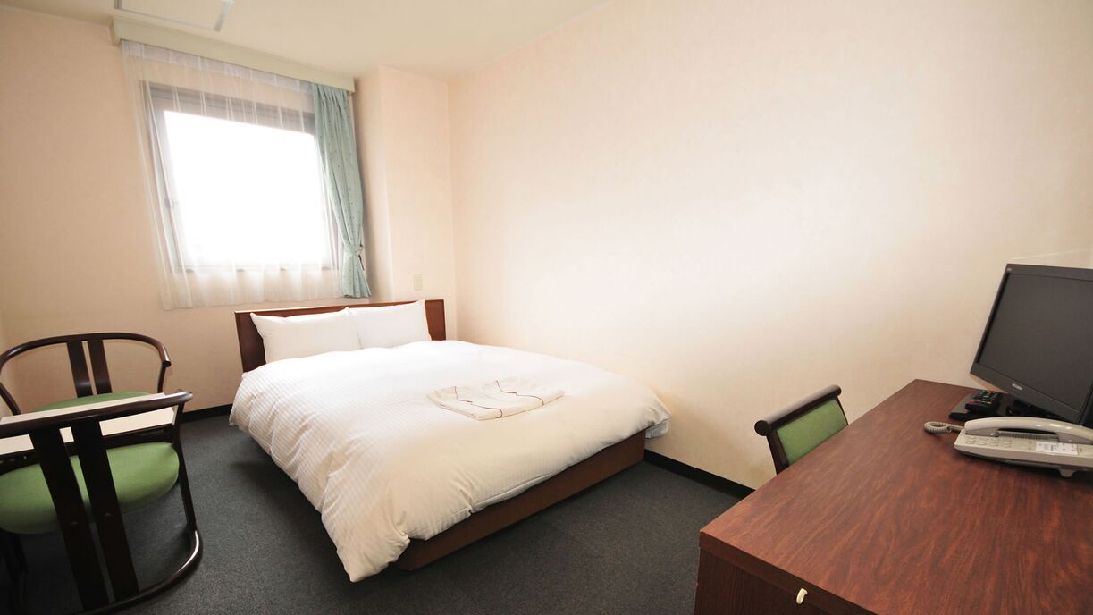 Ein Hotelzimmer mit einem Bett, einem Schreibtisch mit Computer und zwei Stühlen.