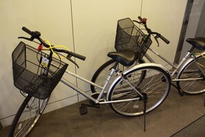 A bicycle with a basket and a seat, parked indoors against a wall. - Hotel Green City (Sendai)