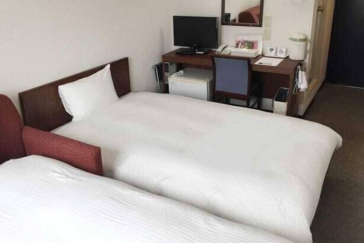 A hotel room with a double bed, a desk with a computer, and a coffee maker.