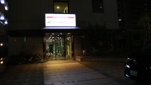 A hotel entrance with a sign, a bicycle, and a car parked outside. - Hotel Green City (Sendai)