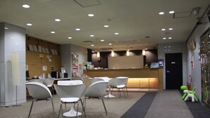 A modern interior with a reception desk, several chairs, and a carpeted floor. - Hotel Green City (Sendai)