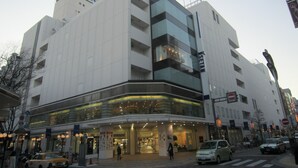 A modern building with a glass facade, multiple floors, and a prominent sign on the top. - Hotel Dorf Shizuoka (Shizuoka)