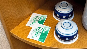 Dos teteras con diseños azul y blanco sobre una superficie de madera, junto con dos paquetes de té verde con texto en japonés.