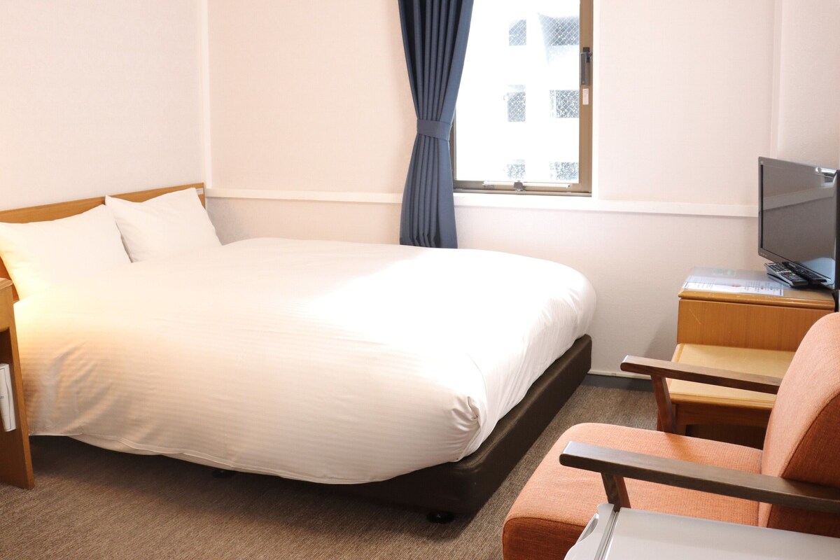 A hotel room with a bed, a TV, a desk, and a chair.