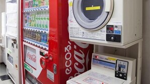 Uma máquina de vendas com o logotipo da Coca-Cola e uma máquina de lavar roupa.