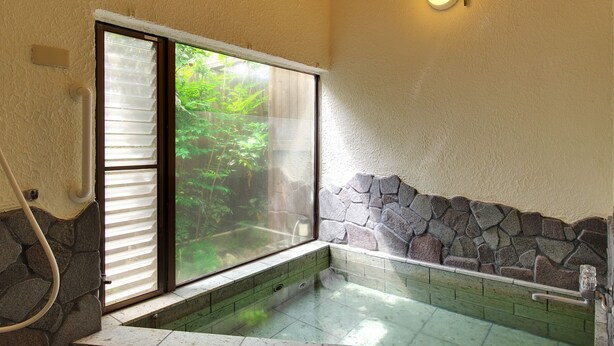 A stone-walled hot tub with a glass window, a stone bench, and a stone wall. - Château Le Fleur (Ito)
