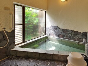 A stone-walled hot tub with a glass window, a stone bench, and a stone wall. - Château Le Fleur (Ito)