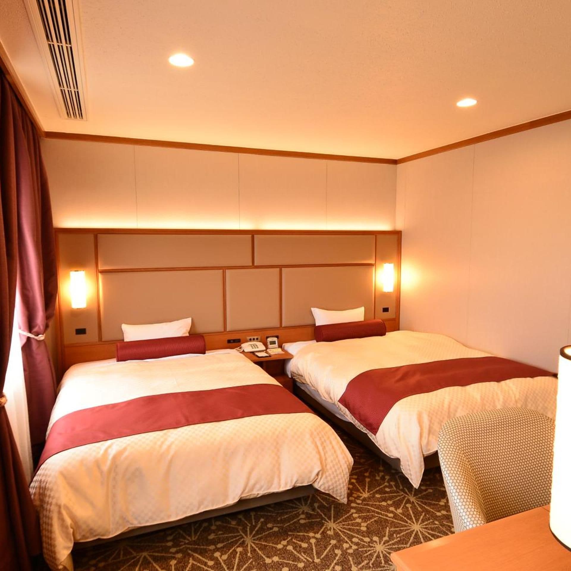 Ein Hotelzimmer mit zwei Betten, einem Nachttisch, einem Telefon und einer Lampe.