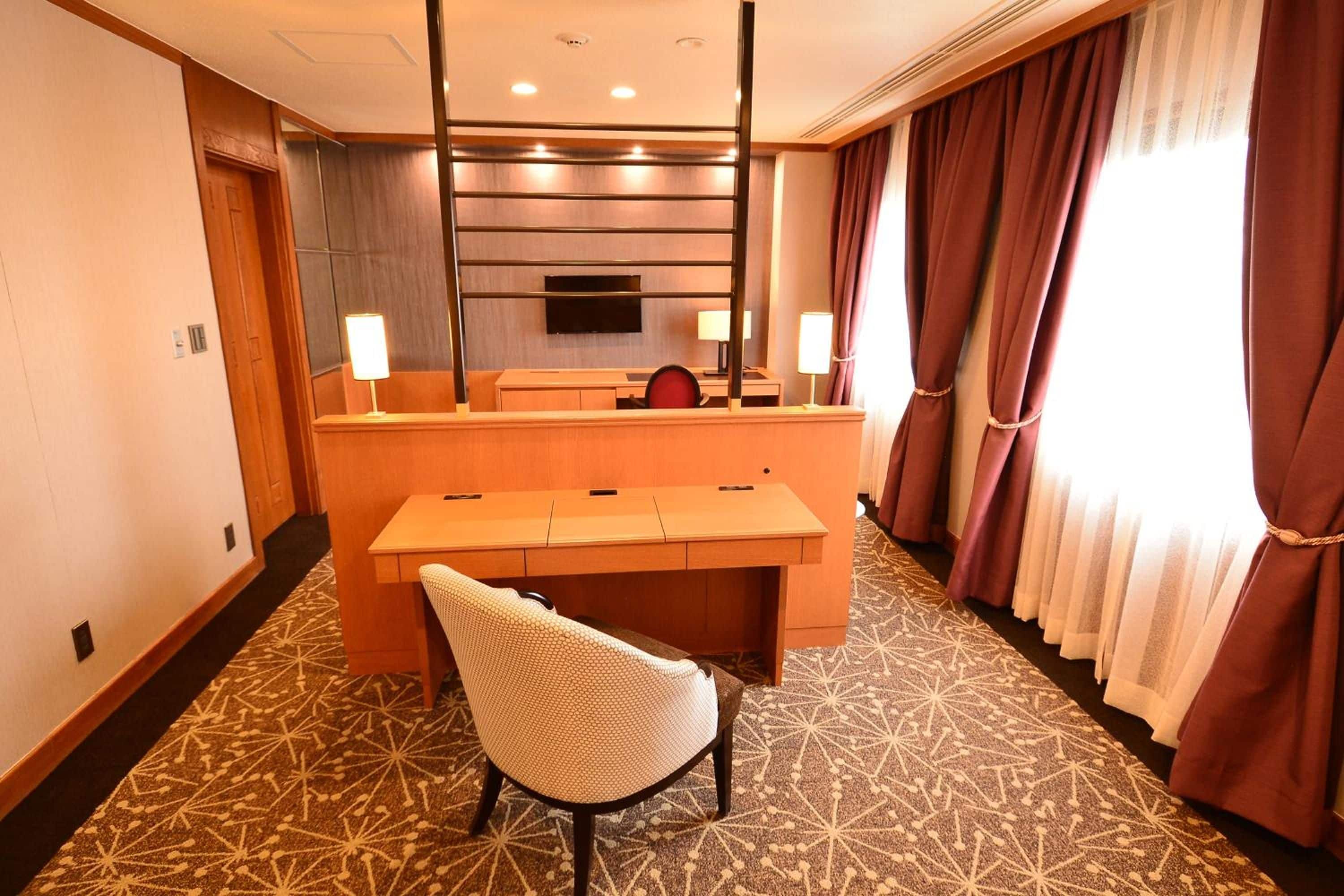 Een hotelkamer met een bureau, stoel en een grote spiegel.