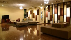 A modern lobby with a sofa, chairs, a TV, and a decorative wall. - Hotel Sunroute Sano (Sano)
