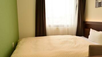 Ein Hotelzimmer mit einem Bett, einem kleinen Tisch und einem Fenster mit Vorhängen.