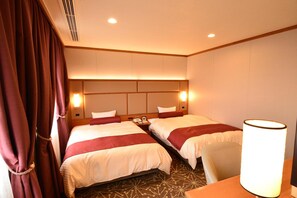 Une chambre d’hôtel avec deux lits, une table de chevet, une lampe et une fenêtre avec des rideaux.