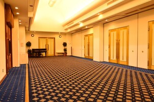 Un pasillo de hotel con alfombra estampada, puertas de madera y un piano.
