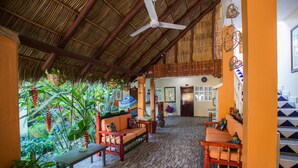 A spacious indoor area with a thatched roof, wooden furniture, and a staircase leading to an upper level. - Hotel Meson de Mita (Punta de Mita)