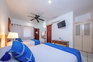A hotel room with two beds, a ceiling fan, a TV, a desk, and a wardrobe.