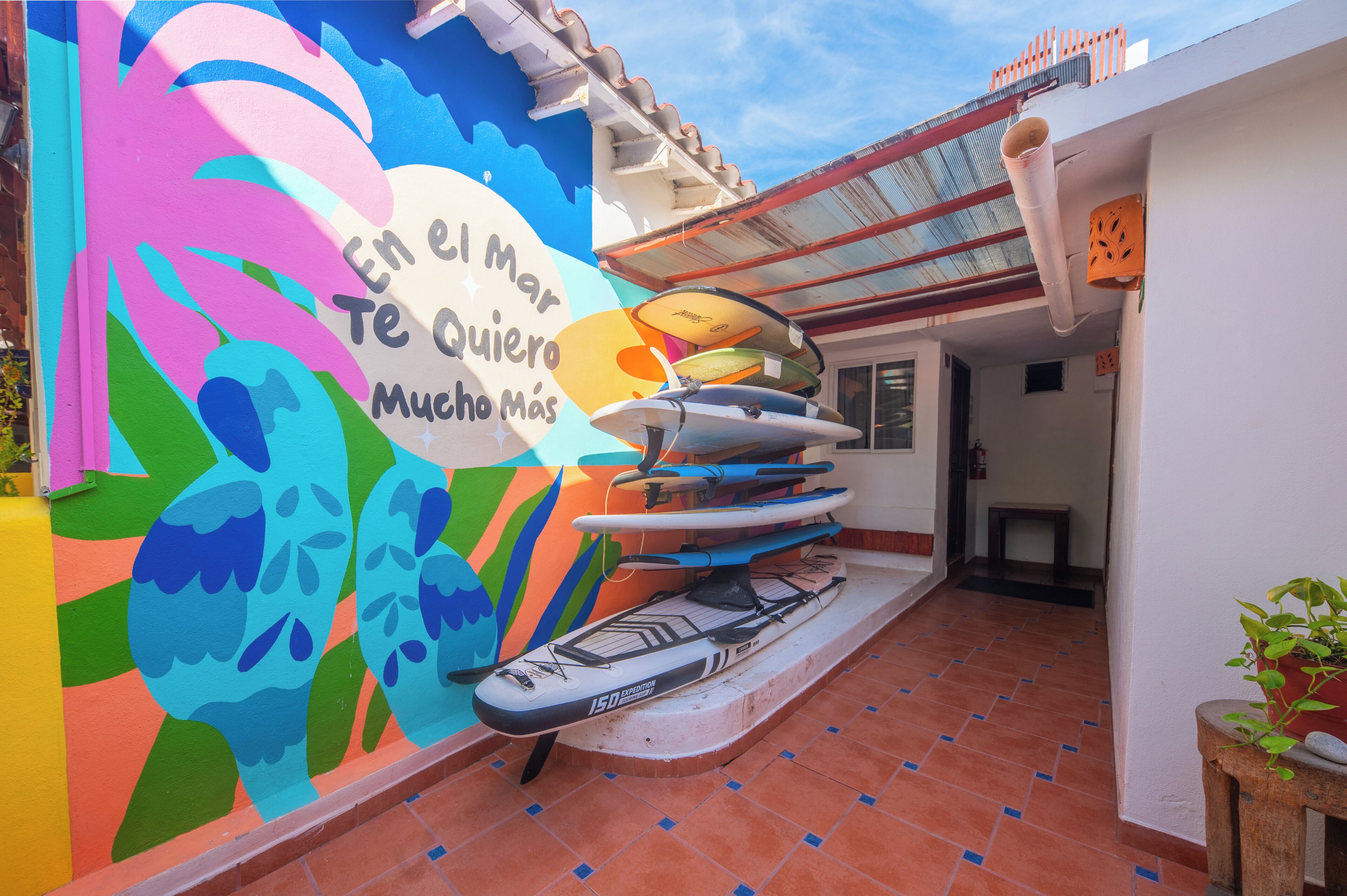 A colorful mural with surfboards, a tiled floor, and a white wall.