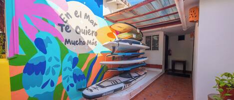 A colorful mural with surfboards, a tiled floor, and a white wall.