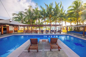 Una piscina al aire libre, sillones reclinables de piscina