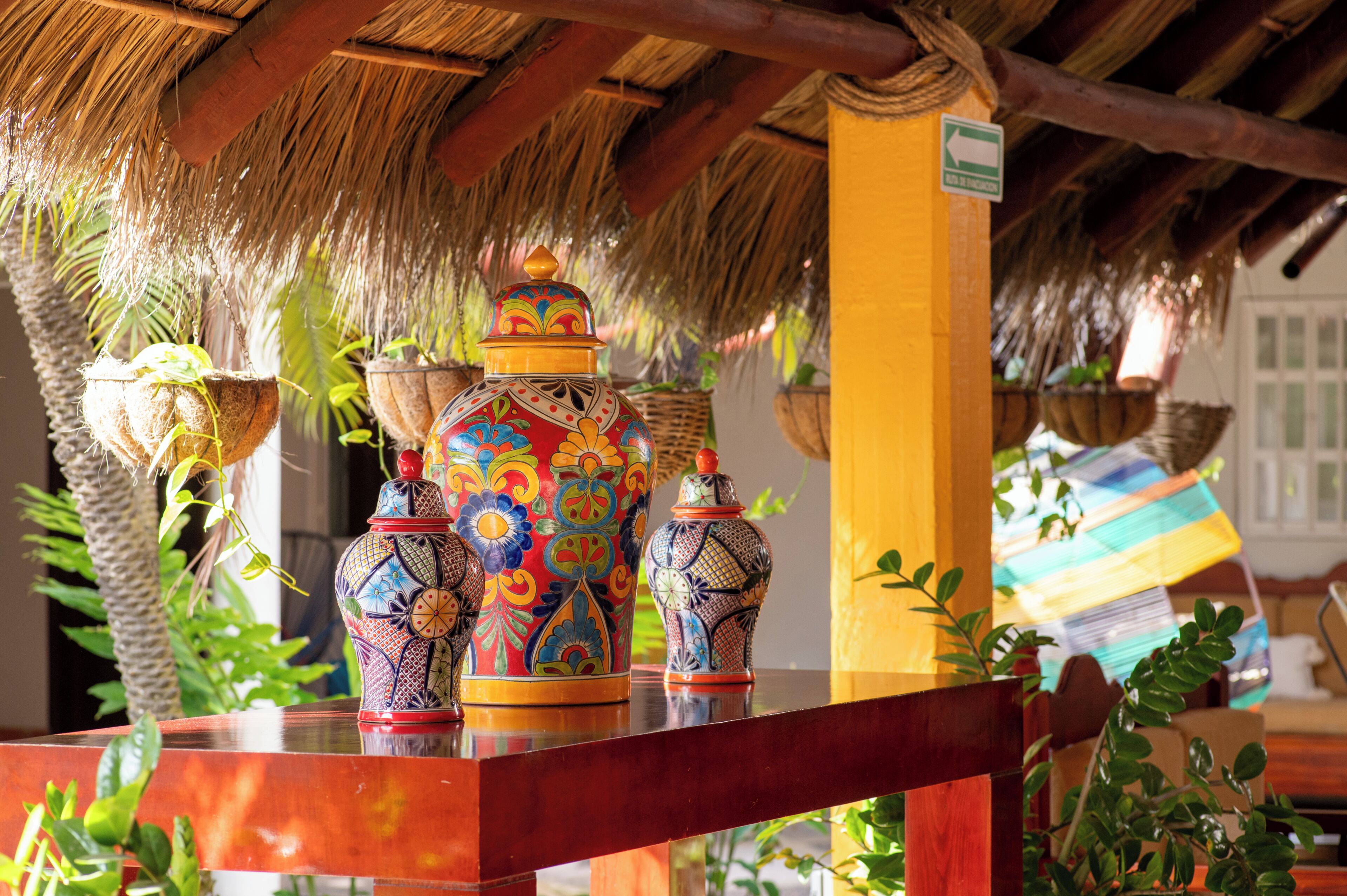 Una estructura de techo de paja con cestas colgantes y jarrones decorativos.