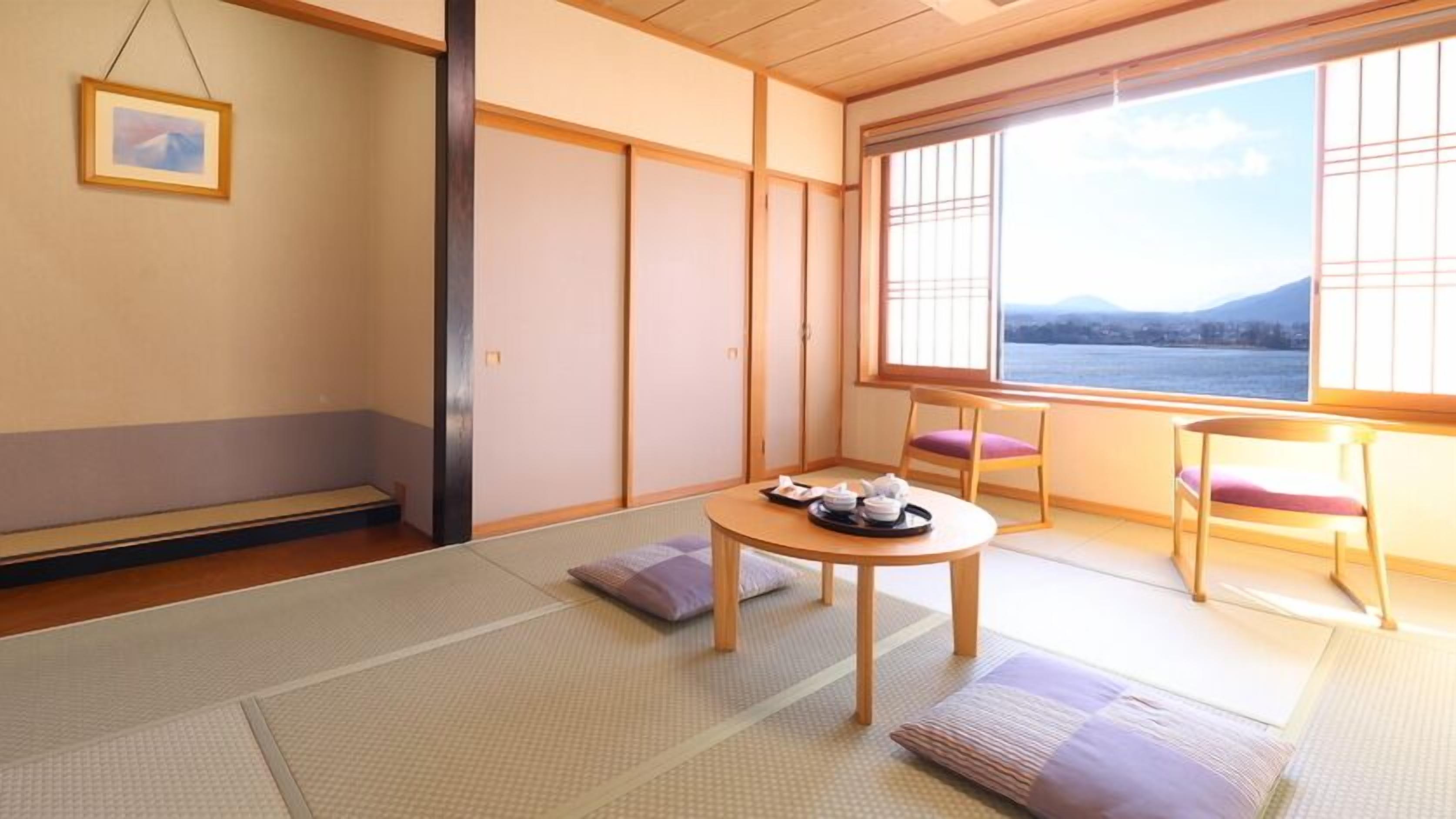 Een traditionele Japanse kamer met tatami vloerbedekking, een lage tafel met theeservies, en uitzicht op een waterpartij door shoji schermen.
