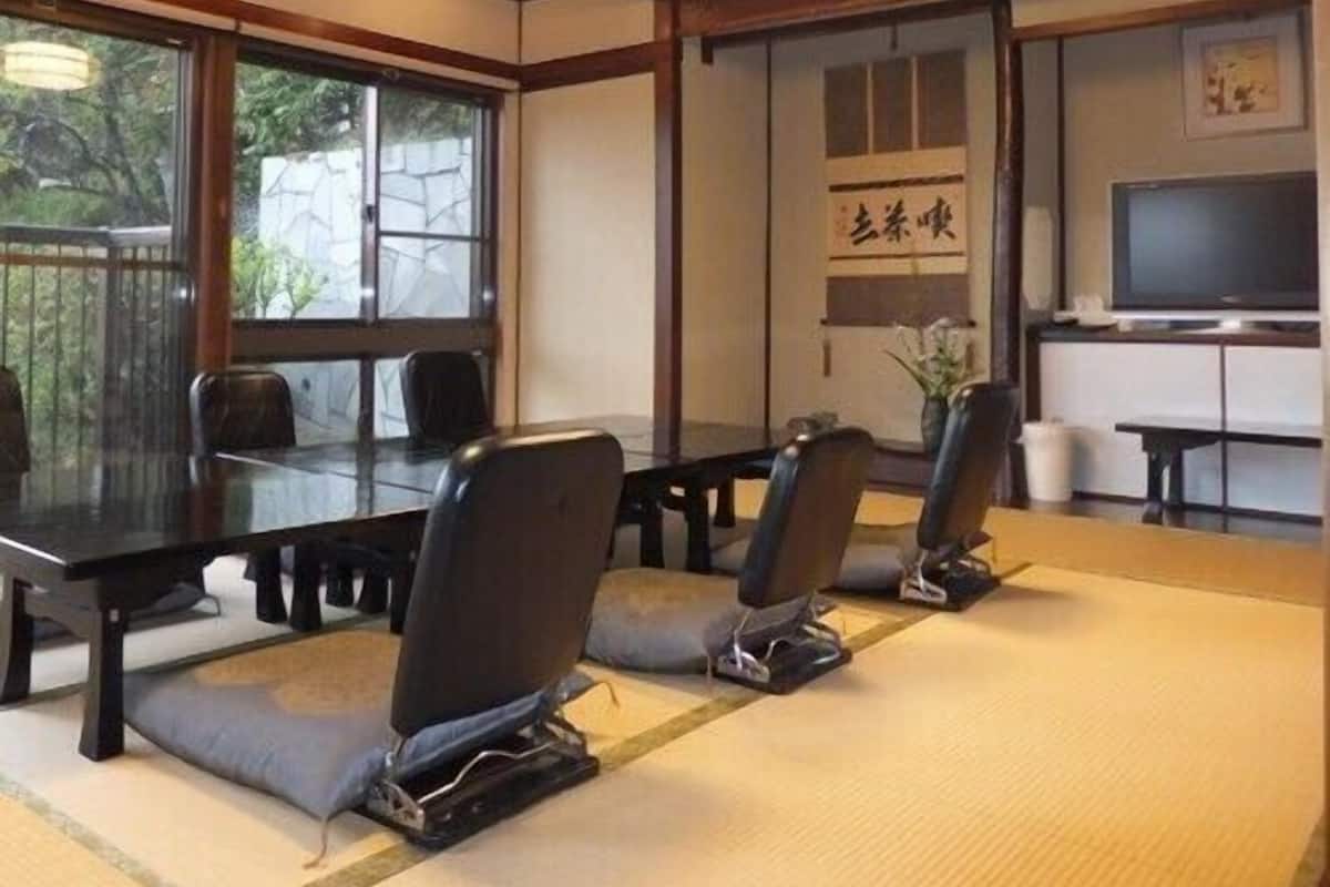 Une salle de conférence avec une longue table, des chaises, un téléviseur et un panneau affichant des caractères japonais.