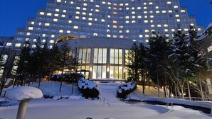 Un hôtel à plusieurs étages doté d’une piscine couverte de neige, entouré d’arbres.