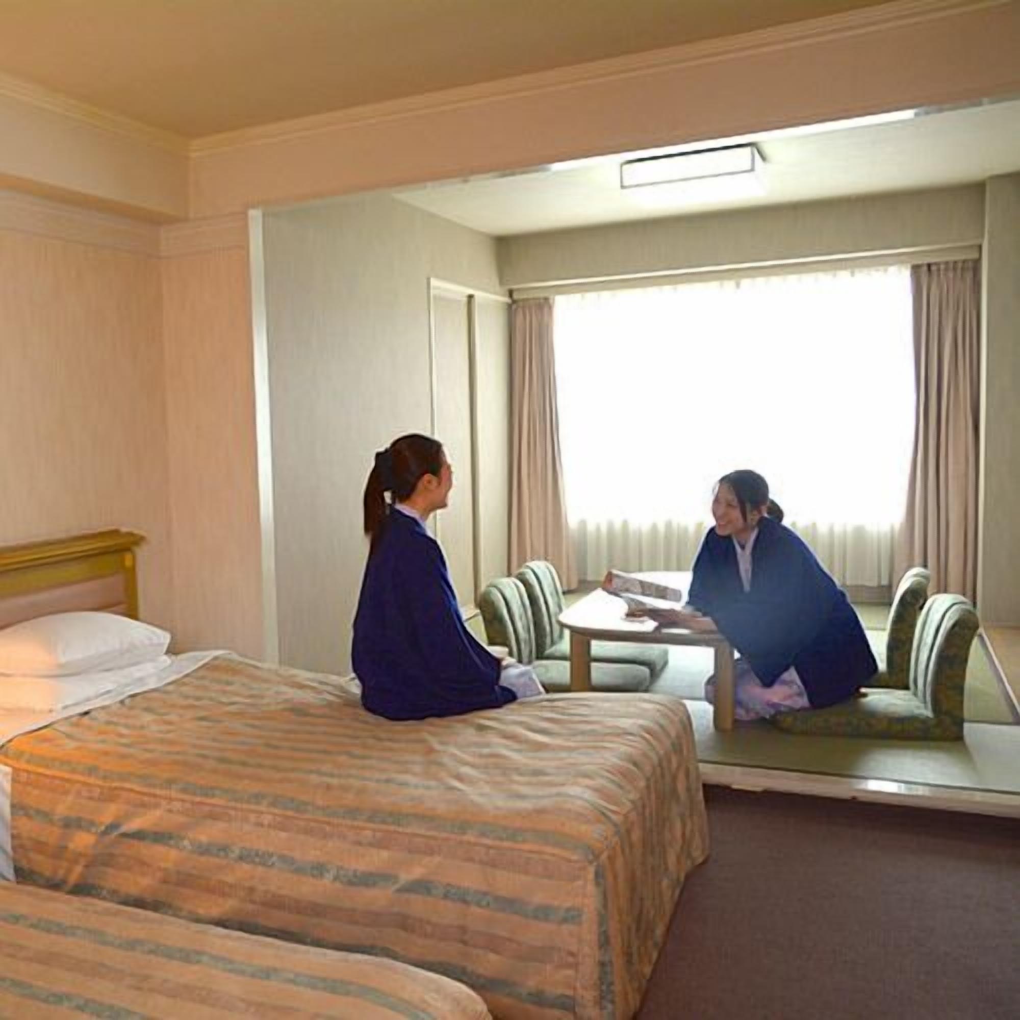 A hotel room with a bed, a table, and a chair.