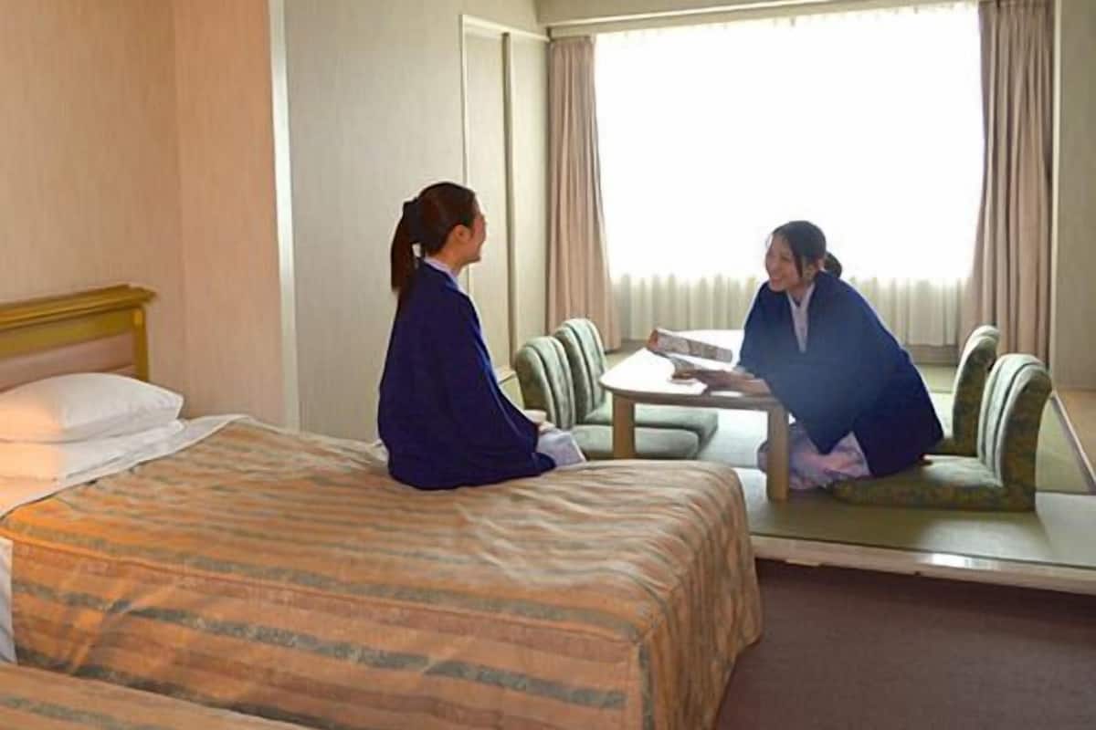 A hotel room with a bed, a table, and a chair.