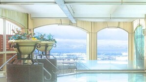 Une piscine avec vue sur le paysage urbain, un espace détente avec une table et une plante décorative.