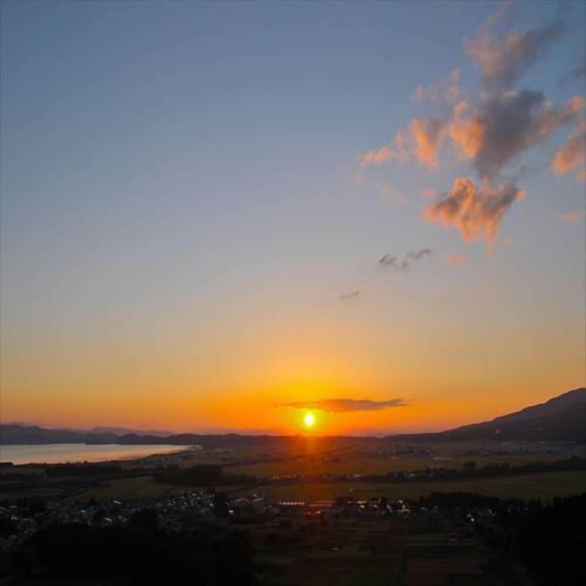 A sunset over a town with visible buildings and a mountain in the background.