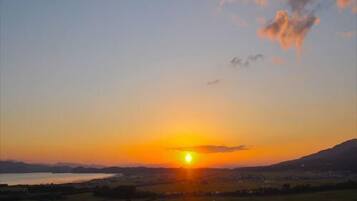 A sunset over a town with visible buildings and a mountain in the background.