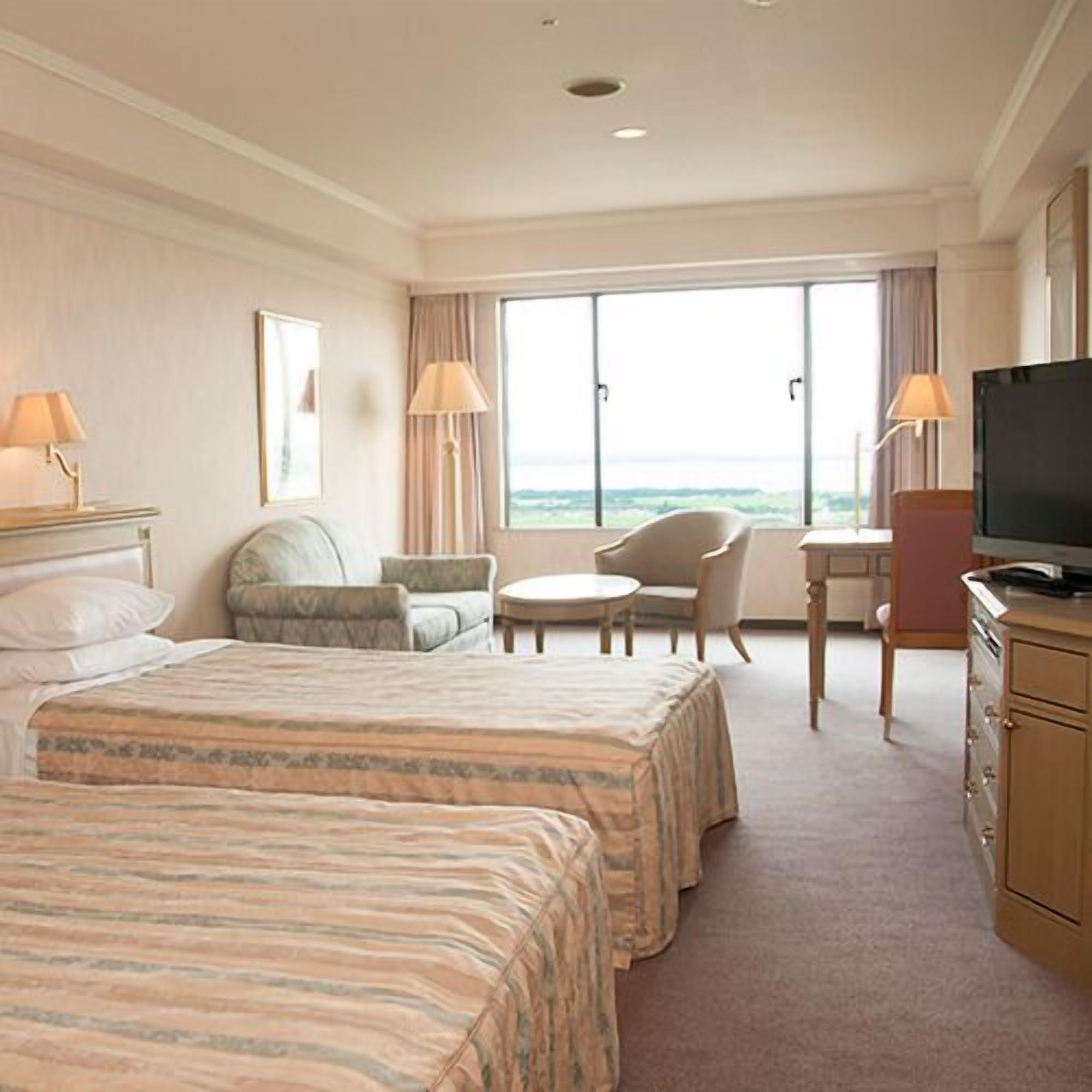 A hotel room with two beds, a TV, a desk, and a chair.